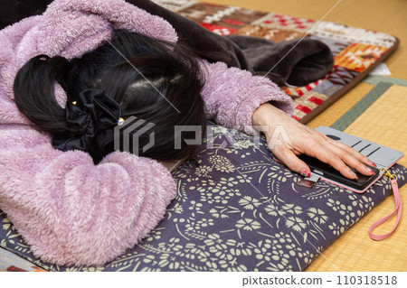 Senior woman taking a nap at a kotatsu in a Japanese-style room Senior woman taking a nap at a kotatsu in a Japanese-style room 110318518