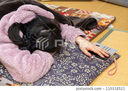 A woman taking a nap at a kotatsu in a Japanese-style room A woman taking a nap at a kotatsu in a Japanese-style room 110318521