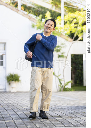 Middle-aged man walking with a backpack on his shoulder Middle-aged man walking with a backpack on his shoulder 110321044