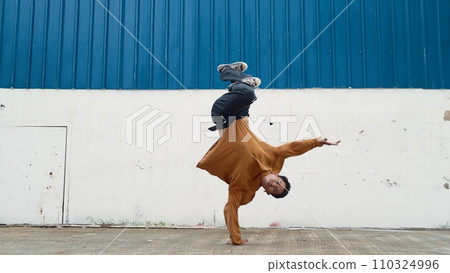 Hispanic man stretch arms and dance street dancing in front of wall. Endeavor. 110324996