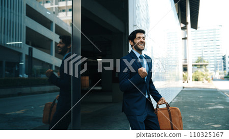 Skilled business man dancing with joyful while walking in glass wall. Exultant. Skilled business man dancing with joyful while walking in glass wall. Exultant. 110325167