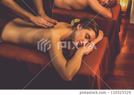 Hot stone massage at spa salon in luxury resort with warm candle light.Quiescent Hot stone massage at spa salon in luxury resort with warm candle light.Quiescent 110325529
