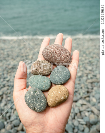 手拿各式色彩的海邊鵝卵石 110329682
