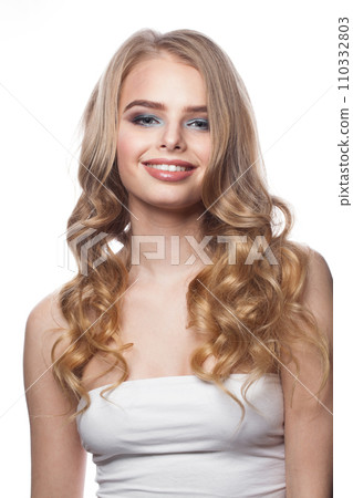 Beautiful young blonde model with long wavy hair, makeup and clean skin on white background.  110332803