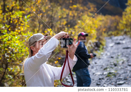 Girl taking pictures of mountain landscape 110333781