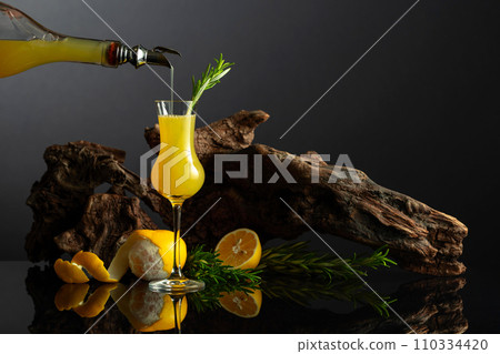Traditional Italian liqueur Limoncello on a black reflective background. Traditional Italian liqueur Limoncello on a black reflective background. 110334420