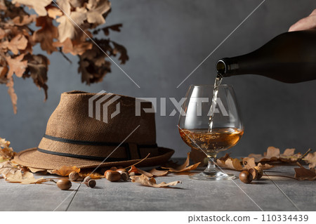 Brandy is poured from a bottle into a glass. Brandy is poured from a bottle into a glass. 110334439