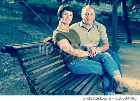 Elderly man and woman embracing on bench Elderly man and woman embracing on bench 110334496