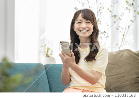 A smiling woman in her 50s with a smartphone 110335168