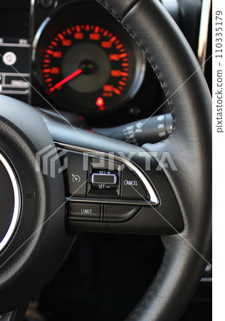 View Of Defocused Speedometer With Red Backlight Through Steering Wheel With Speed Control Buttons On It  110335179
