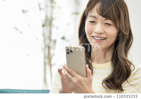 一位50多歲的女性經營智能手機 一位50多歲的女性經營智能手機 110335255