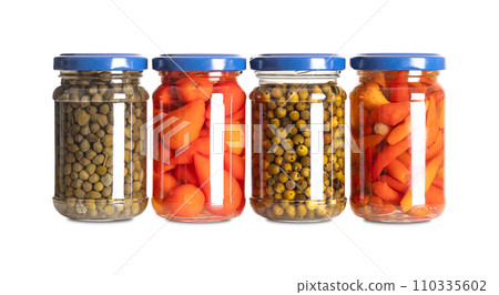Pickled spices in small glass jars. From left to right capers, hot red baby peppers, green peppercorns, and piri piri chilis. Pasteurized and preserved in a brine of water, vinegar and salt. Photo. 110335602