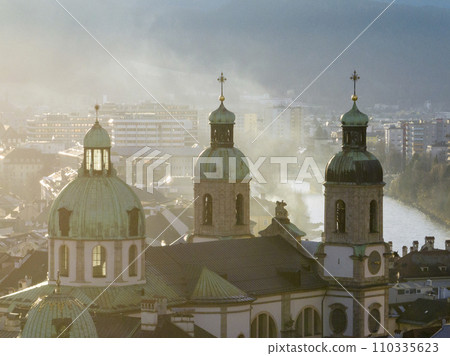 Bell towers of Cathedral of St. James in Innsbruck, Austria. Church Domes in Soaft Light at Foggy Evening sunset time 110335623