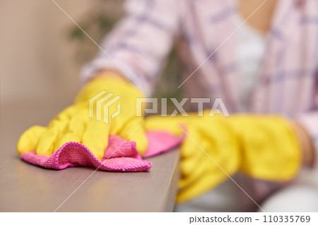 young woman in gloves cleaning and wiping table with microfiber cloth. chores at home. Housekeeping young woman in gloves cleaning and wiping table with microfiber cloth. chores at home. Housekeeping 110335769