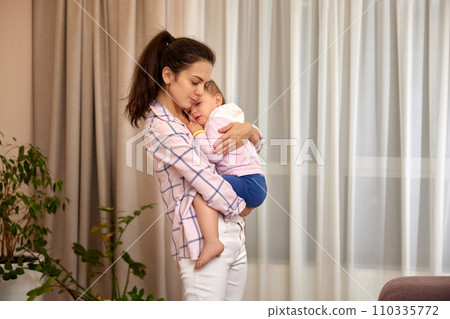 loving mother holding crying baby on hands at home 110335772