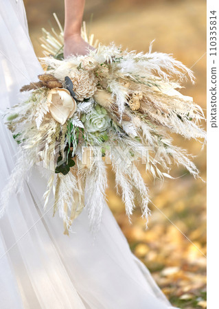 hands of the bride holding beautiful autumn bouquet outdoor 110335814