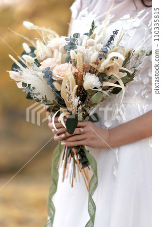 hands of the bride holding beautiful autumn bouquet outdoor 110335815