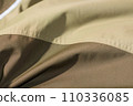protective work clothes in beige and brown colors. Factory stitches on thick fabric. Close-up texture 110336085