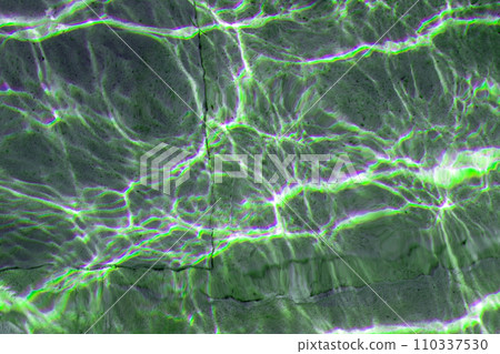 Colorful green sun glare on the water in the fountain with an old stone floor, unusual abstract texture 110337530