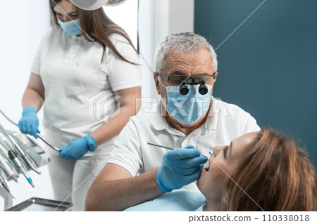 Dentist and assistant work together to ensure highest level of treatment for patient. Their cooperation, mutual understanding and synchronized work guarantee high-quality treatment and healthy smile 110338018