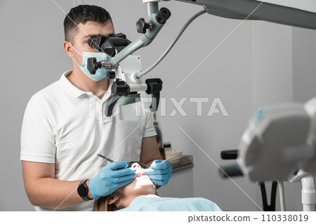 A meticulous and highly qualified dentist carefully examines each patient's tooth under a microscope, identifying and solving any dental problems with incredible accuracy. A meticulous and highly qualified dentist carefully examines each patient's tooth under a microscope, identifying and solving any dental problems with incredible accuracy. 110338019