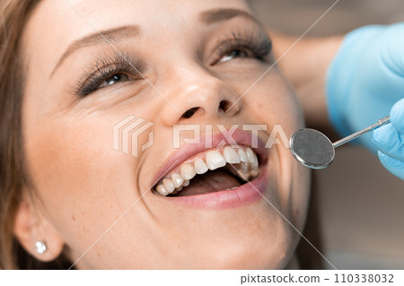 The dentist carefully works on the patient's smile, creating the perfect balance between aesthetics and health. In dental chair, patient confidently maintains dialogue about taking care of her smile. The dentist carefully works on the patient's smile, creating the perfect balance between aesthetics and health. In dental chair, patient confidently maintains dialogue about taking care of her smile. 110338032