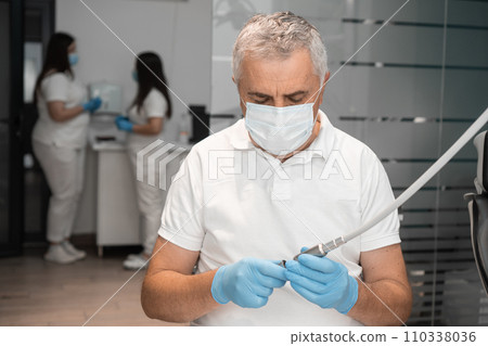 The senior dentist prepares the instrument for the appointment. The team of dentists collaborates in a focused way, going through all aspects X-ray, creating an area mutual trust and responsibility. 110338036