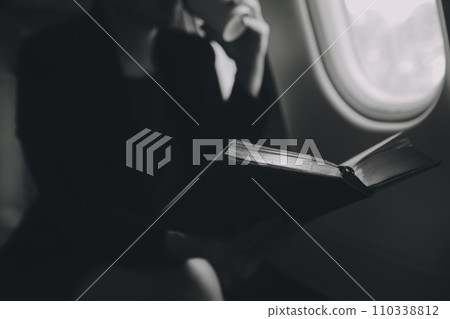 Blonde female tourist checking incoming notification on smartphone sitting on seat of airplane with netbook.Young businesswoman share media from telephone on laptop computer during plane flight Blonde female tourist checking incoming notification on smartphone sitting on seat of airplane with netbook.Young businesswoman share media from telephone on laptop computer during plane flight 110338812