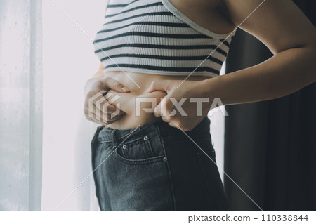 Women body fat belly. Obese woman hand holding excessive belly fat. diet lifestyle concept to reduce belly and shape up healthy stomach muscle. Women body fat belly. Obese woman hand holding excessive belly fat. diet lifestyle concept to reduce belly and shape up healthy stomach muscle. 110338844