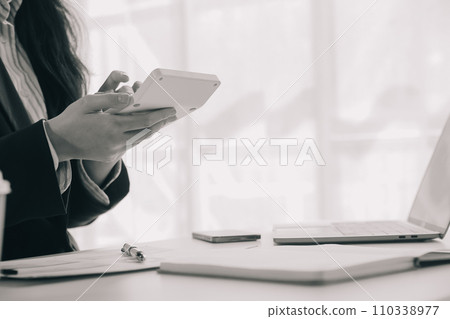 Businessman using a calculator to calculate numbers on a company's financial documents, he is analyzing historical financial data to plan how to grow the company. Financial concept. 110338977