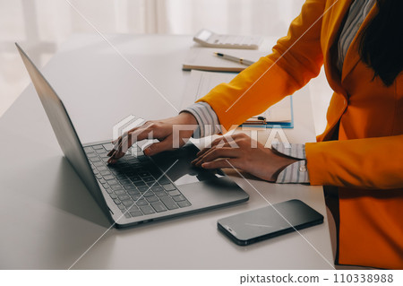 Business woman using mobile phone during working on laptop computer, surfing the internet, searching business data at modern office. Asian businesswoman online working on computer at workplace Business woman using mobile phone during working on laptop computer, surfing the internet, searching business data at modern office. Asian businesswoman online working on computer at workplace 110338988
