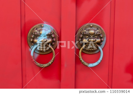 Old bronze door knobs with the shape of a lion's head on red door 110339014