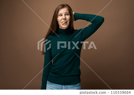 Charming young woman in a green turtleneck on a brown background 110339084