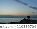 Two people standing at dusk 110339704