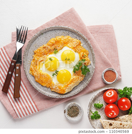 Fried eggs with cheese and sesame served on plate over napkin, vegetarian breakfast 110340569