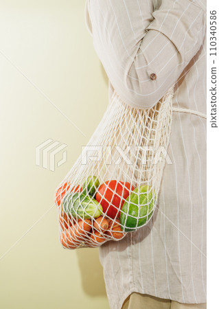 different vegetables in the shopping bag that hangs on the girl's shoulder 110340586