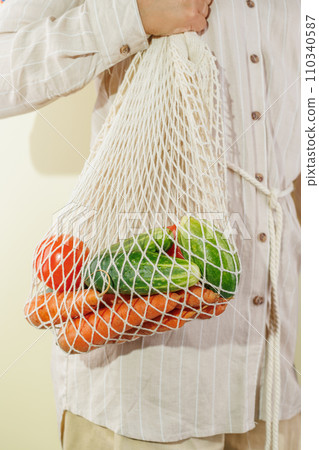 different vegetables in the shopping bag that hangs on the girl's shoulder 110340587