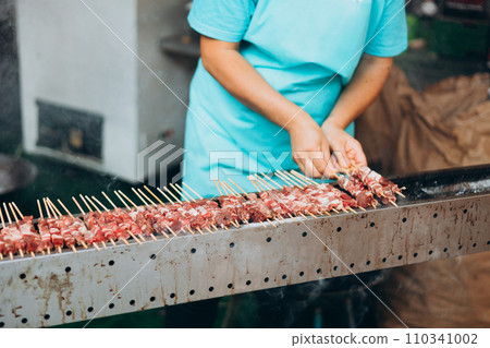 Focus selection: Pork grilled vendors, street food available in Thailand. Hand of a hawker grilled pork and beef over an open fire. Selling traditional hot food at the Fair 110341002