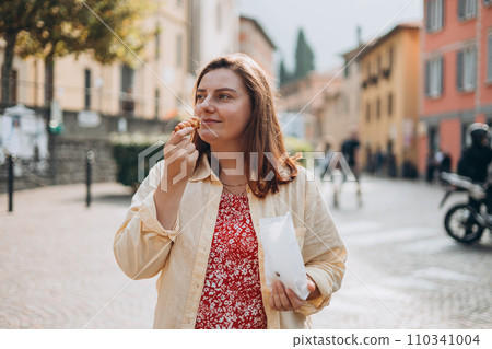 Happy woman holding Sicilian cannolo tube pastry filled with cream. Travel, Italy and holidays concept. Young women eating traditional delicious cake cannoli, Traveling Europe in summer Happy woman holding Sicilian cannolo tube pastry filled with cream. Travel, Italy and holidays concept. Young women eating traditional delicious cake cannoli, Traveling Europe in summer 110341004