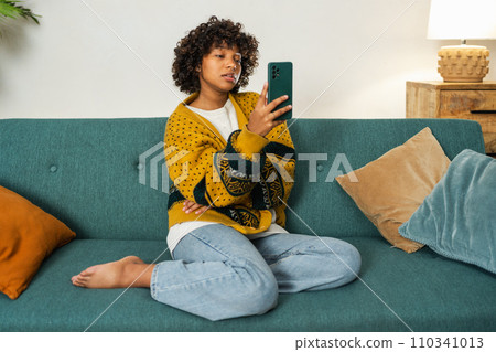 African American girl holding smartphone having video chat. Female blogger chatting with best friends in social network. Young woman having virtual meeting online chat video call at home African American girl holding smartphone having video chat. Female blogger chatting with best friends in social network. Young woman having virtual meeting online chat video call at home 110341013