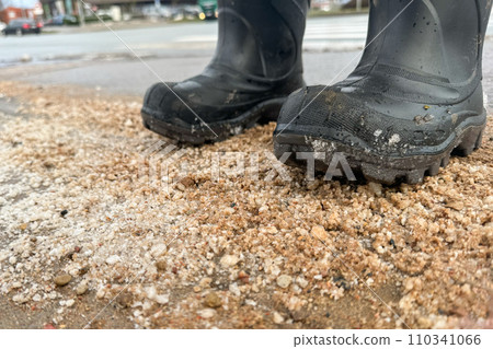 Standing with boots on a dirty street, salt and sand on the road in winter 110341066