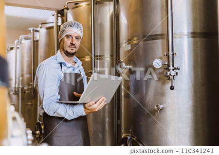 Winemaker professional working in modern large winery factory liquor alcohol drinks industry quality control and fermentation monitor vintage color tone 110341241