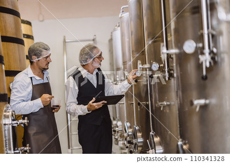 Winemaker professional working in modern large winery factory liquor alcohol drinks industry quality control and fermentation monitor vintage color tone 110341328