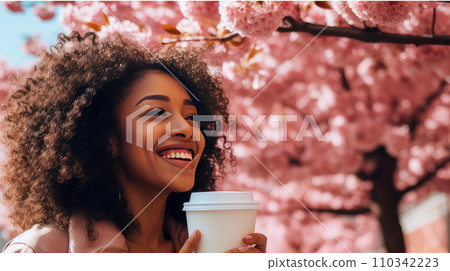 Modern happy young smiling dark-skinned African woman with a glass of coffee against the backdrop of pink cherry blossoms and metropolis city. 110342223