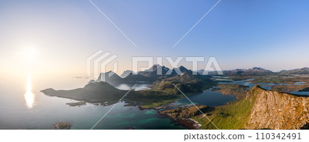 Midnight sun illuminates Offersoykammen and Nappstraumen's peaks and inlets in Lofoten, Norway 110342491