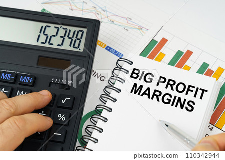 On the table there is a calculator, reports with graphs and a notepad with the inscription - Big Profit Margins 110342944