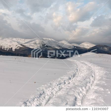 Sledge trace and footprints on winter mountain hill top 110343007