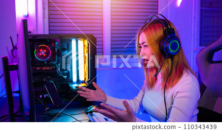 Game over you lose. Angry Asian gamer wearing gaming headphones playing joystick console video game on computer PC neon light at home feeling sad disappointed about game losing, player unhappy E-Sport 110343439