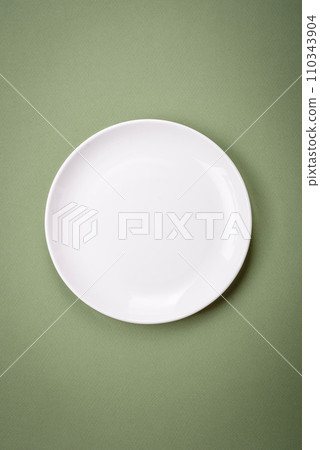 Empty round ceramic plate on a plain background, flatley with copy space 110343904