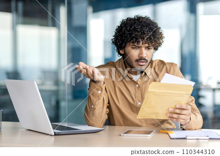 Sad unsatisfied and unhappy business man inside office at workplace, man received mail envelope fox with notification message with bad news, worker reads disappointed. 110344310